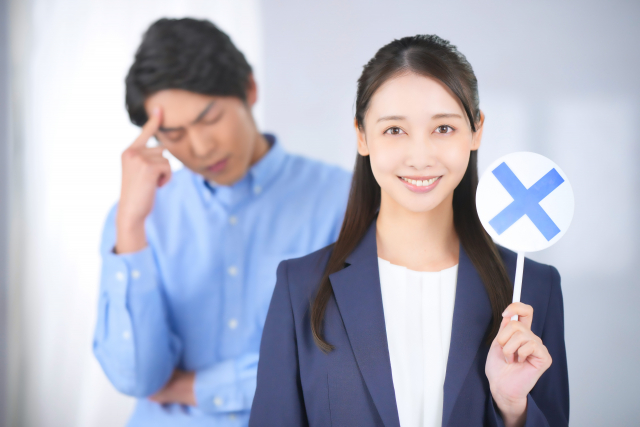 バツの札を持っている女性