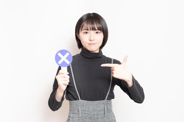 バツの札をあげている女性